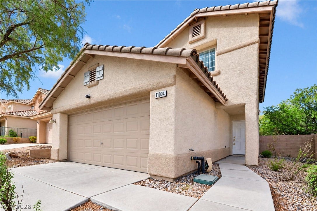 A classic stucco exterior features a tiled roof and an attached garage.