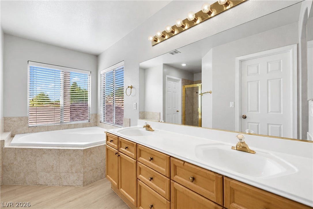 Natural light pours over a double vanity and deep soaking tub.