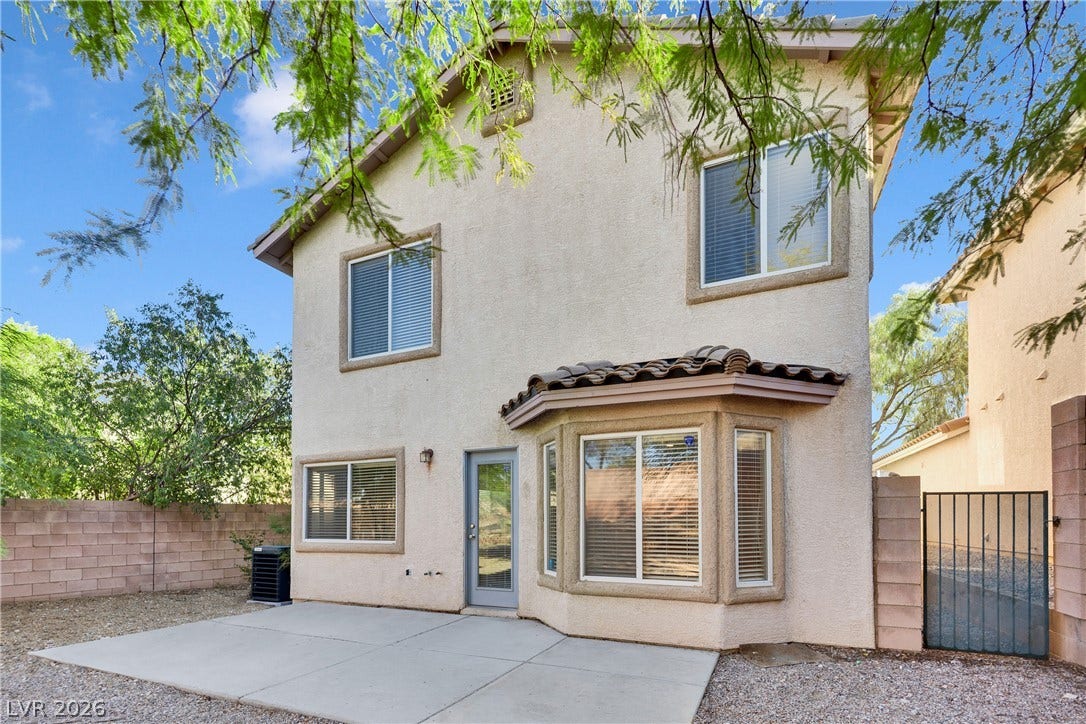 A spacious concrete patio overlooks the private backyard with a secure side gate.