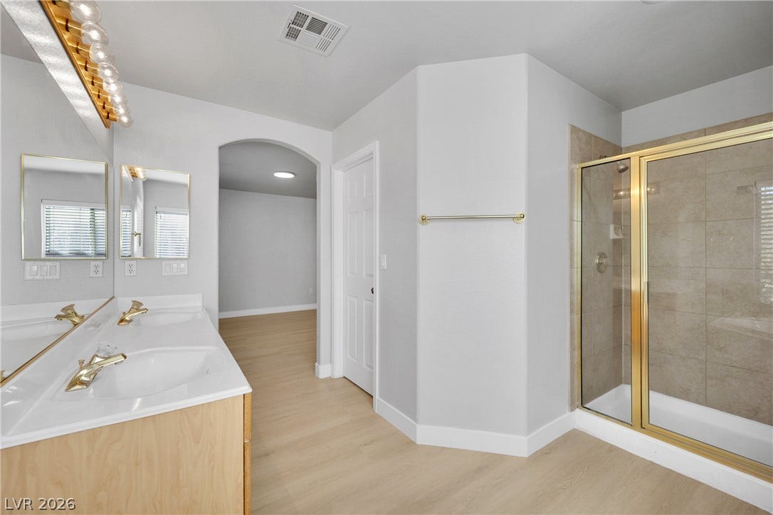 Clean lines and warm wood flooring define this master bathroom with a walk-in shower.
