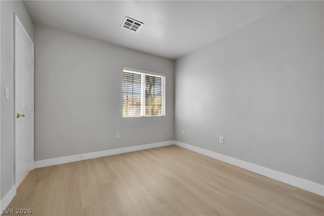 Smooth wood-style flooring and a wide window with blinds define this versatile room.