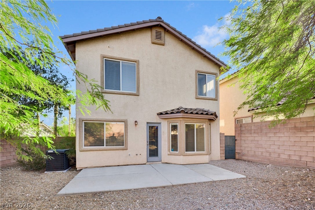A spacious concrete patio extends from the stucco exterior under a classic tiled roof.