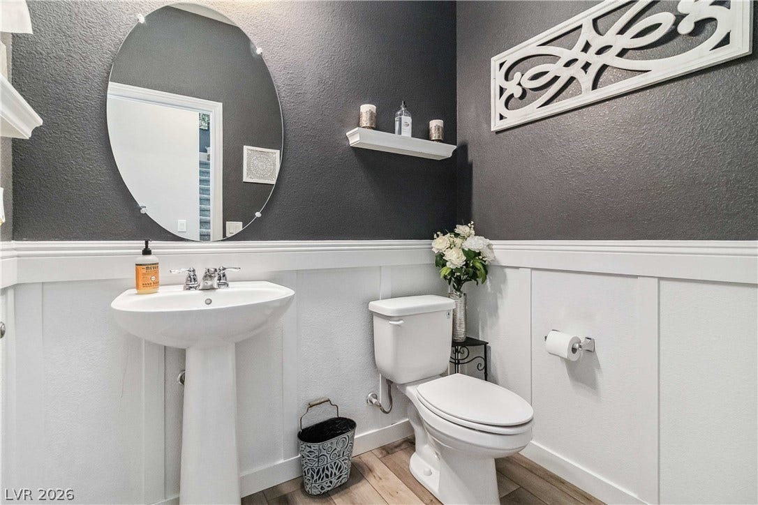 Elegant wainscoting and warm wood-look flooring define this charming powder room.