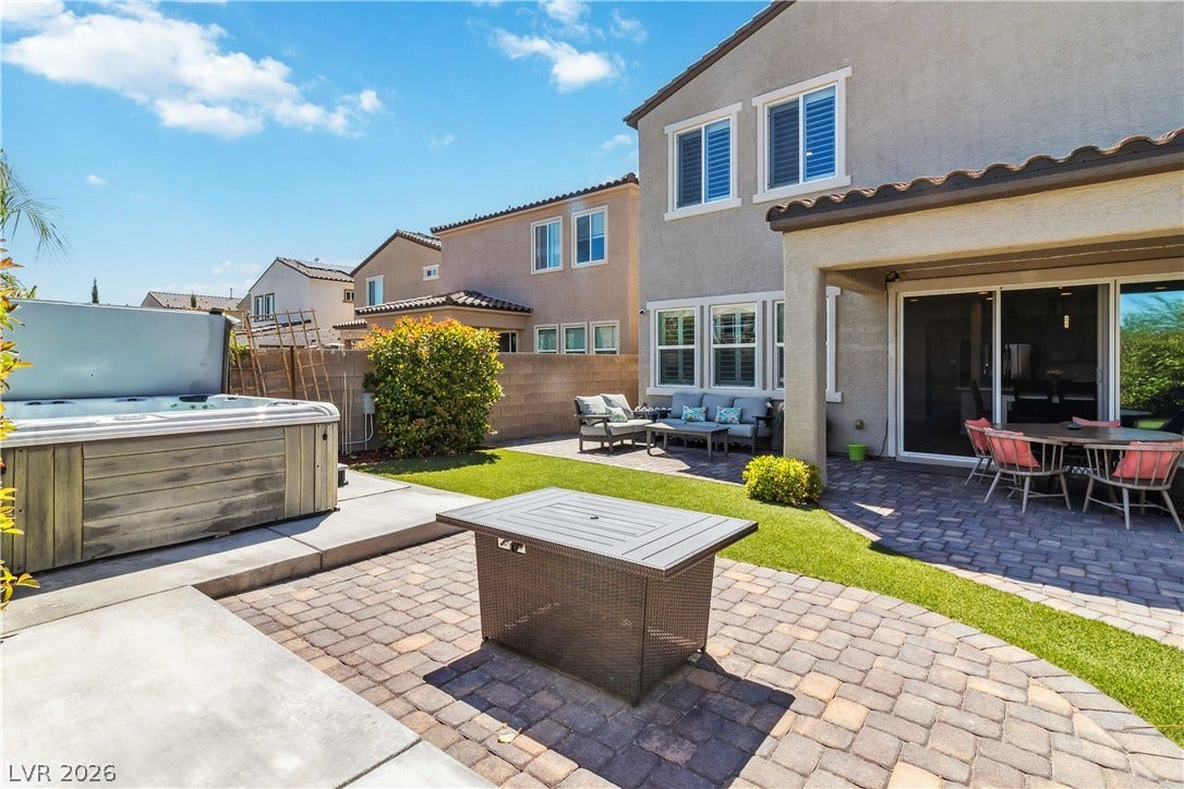 An inviting backyard features a paved patio, covered porch, and private spa.