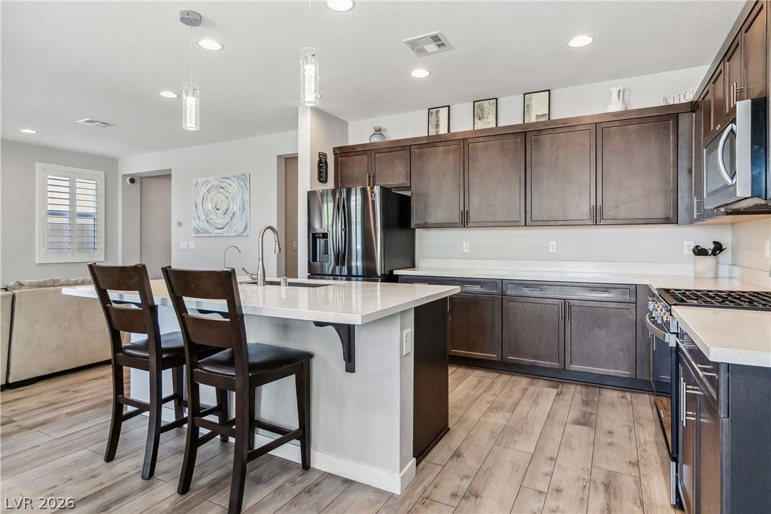 Rich wood cabinetry contrasts beautifully with pale stone countertops in this modern open kitchen.