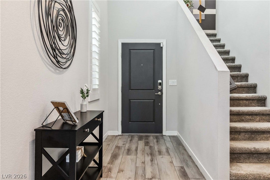 An inviting entrance foyer welcomes guests with durable wood-look flooring and a soaring ceiling.