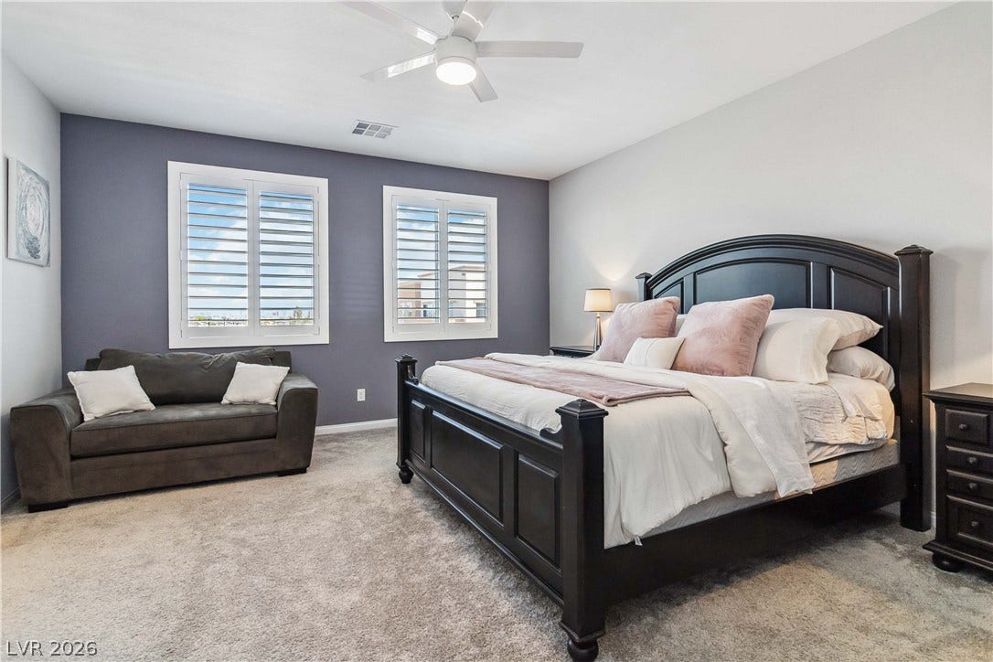 Plentiful natural light streams through plantation shutters into this spacious bedroom.