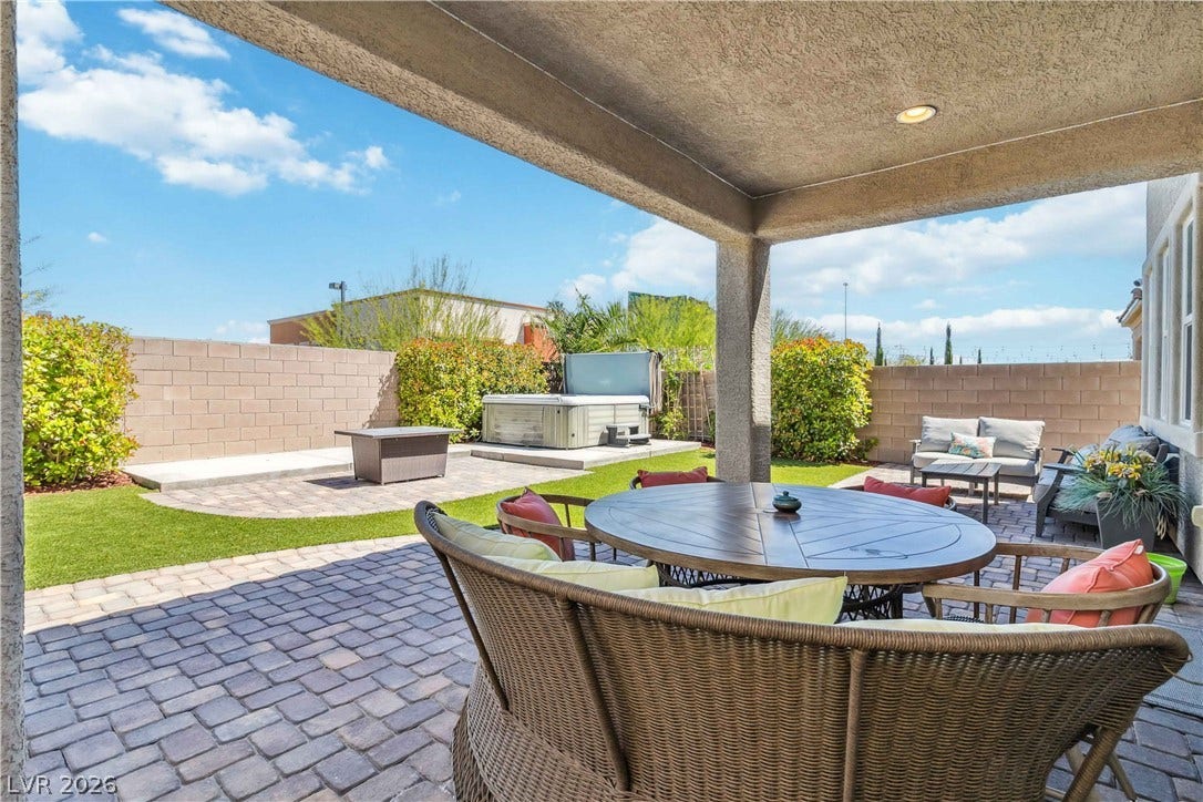 An inviting covered patio opens directly onto a private backyard with beautifully paved areas.