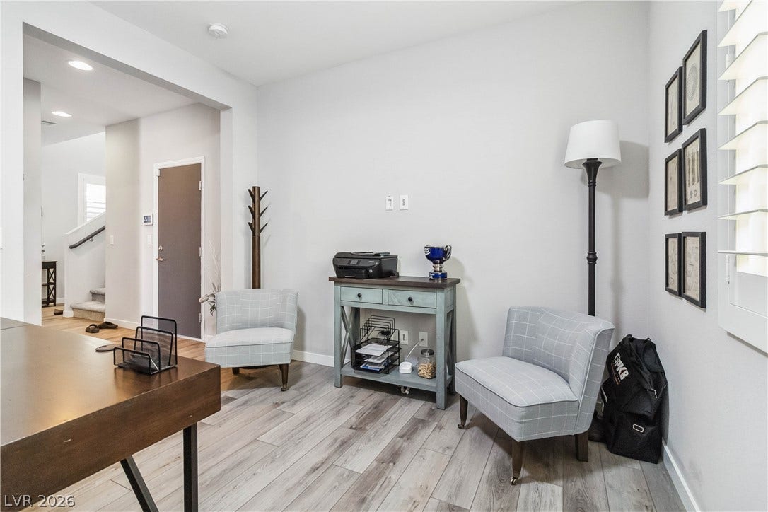 Gleaming wood-look floors anchor this versatile room boasting custom plantation shutters.