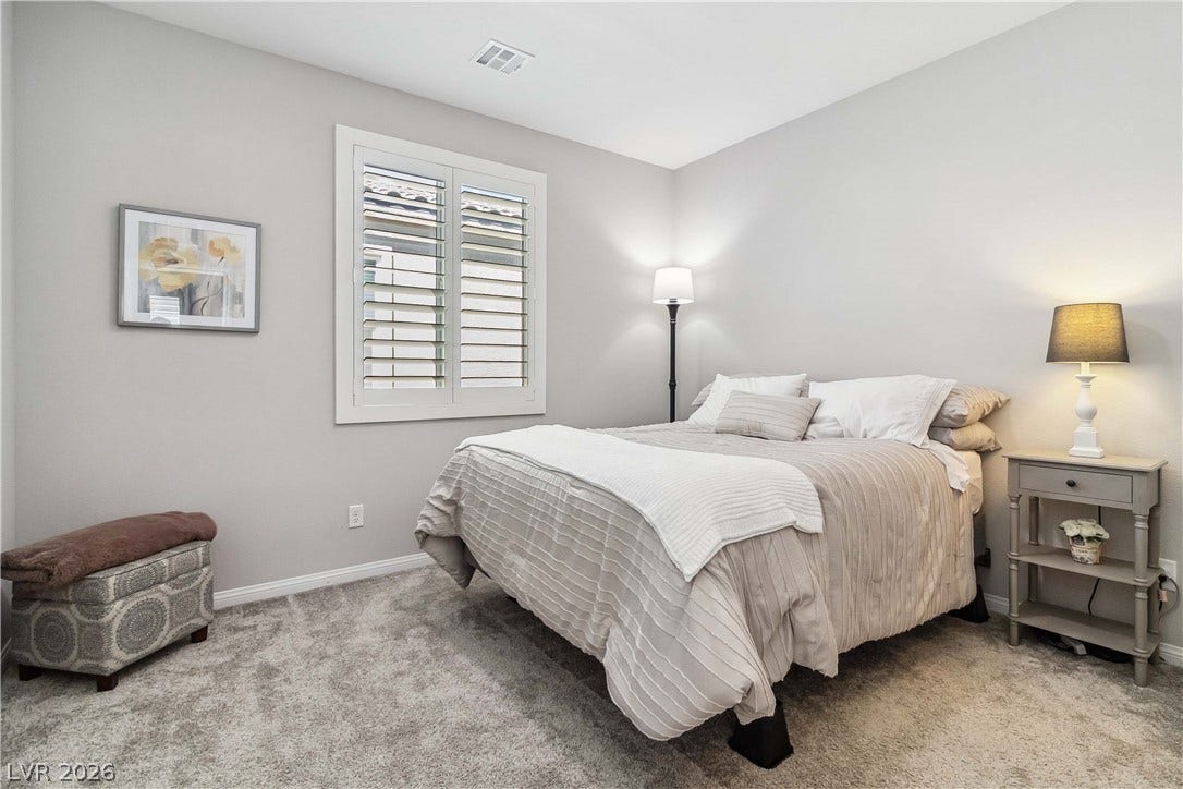 Plush wall-to-wall carpeting and plantation shutters define this inviting bedroom space.