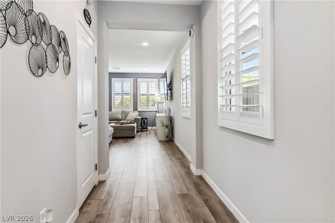 Streamlined hallway featuring handsome wood-look plank flooring leads directly into the main living areas.