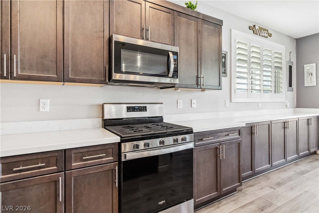 Rich wood cabinetry contrasts beautifully with clean white countertops and updated stainless steel appliances.