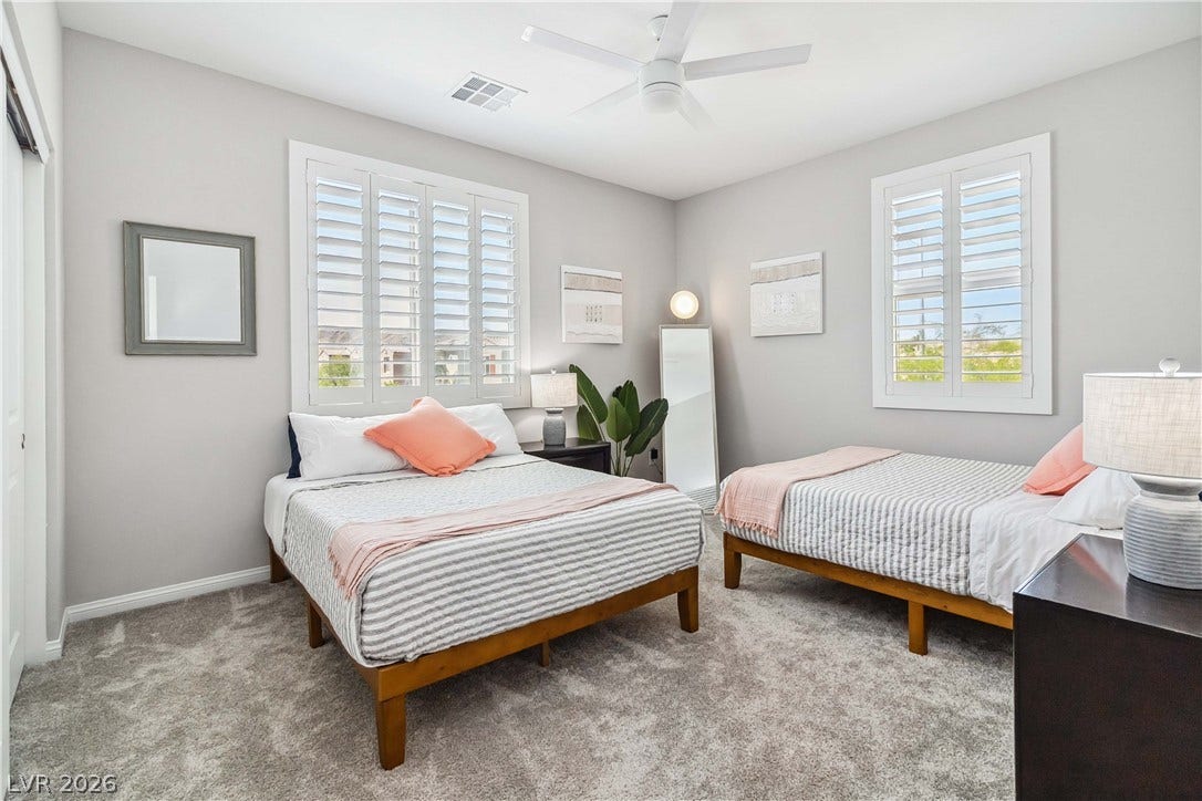 Plush carpeting and plantation shutters define this inviting bedroom space.