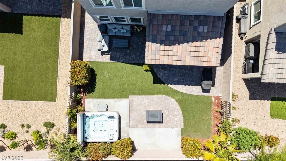 An aerial view showcases a meticulously designed backyard featuring a spa and paved patio spaces.
