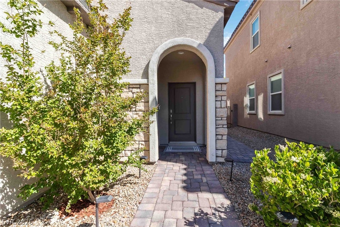 An arched entryway and stone accents welcome guests along a paved stone pathway.