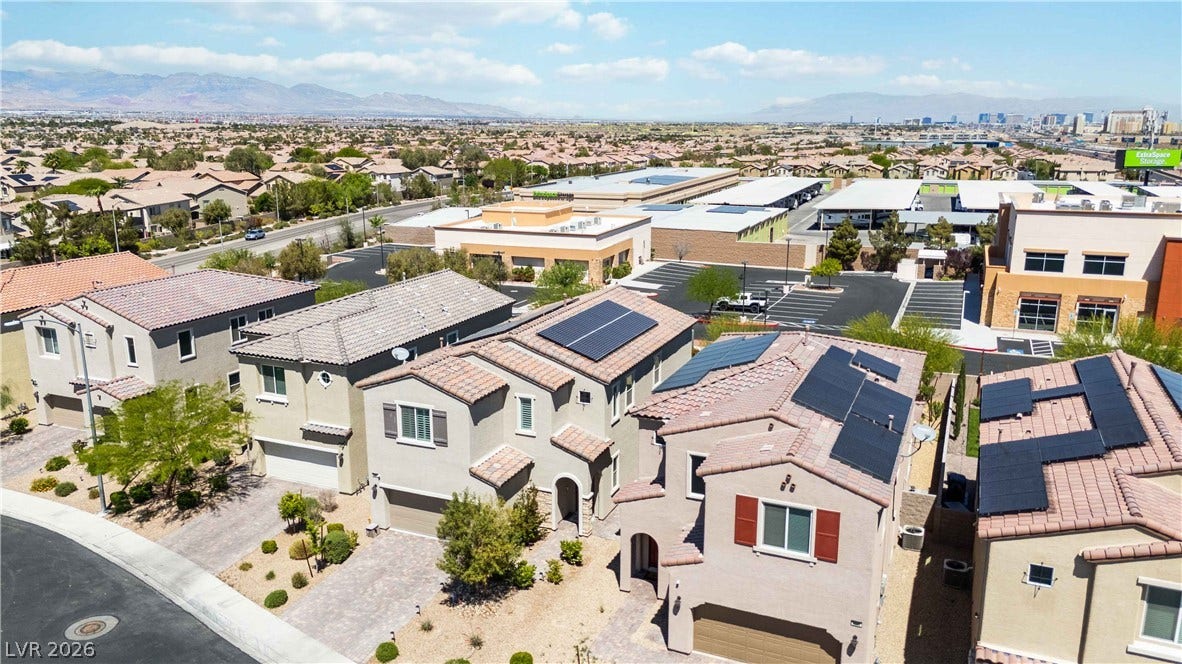 Solar panels line the roofs of these modern multi-level suburban homes under clear desert skies.