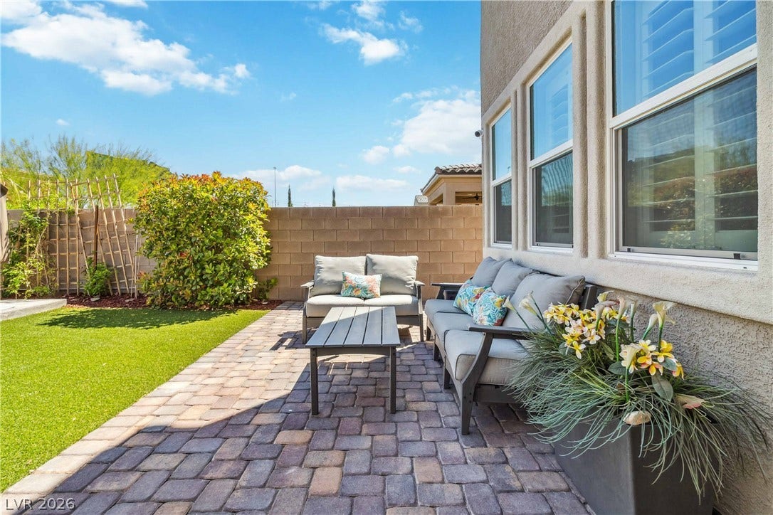 A private paver patio offers an inviting outdoor retreat alongside the manicured lawn.