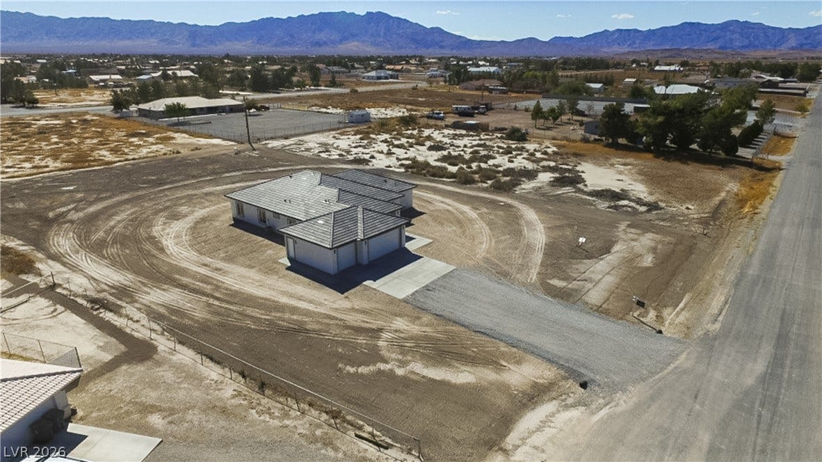 An aerial perspective showcases a tile-roofed home nestled against a majestic mountain backdrop.