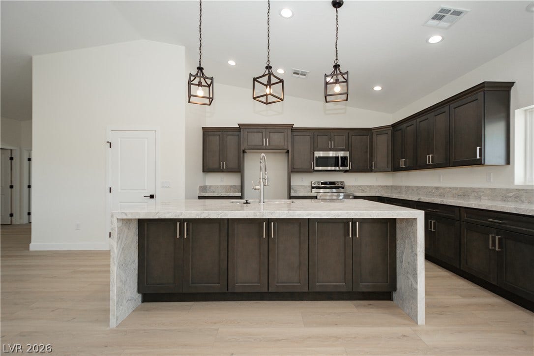 Dark cabinetry beautifully contrasts with light wood-style flooring in this modern kitchen design.