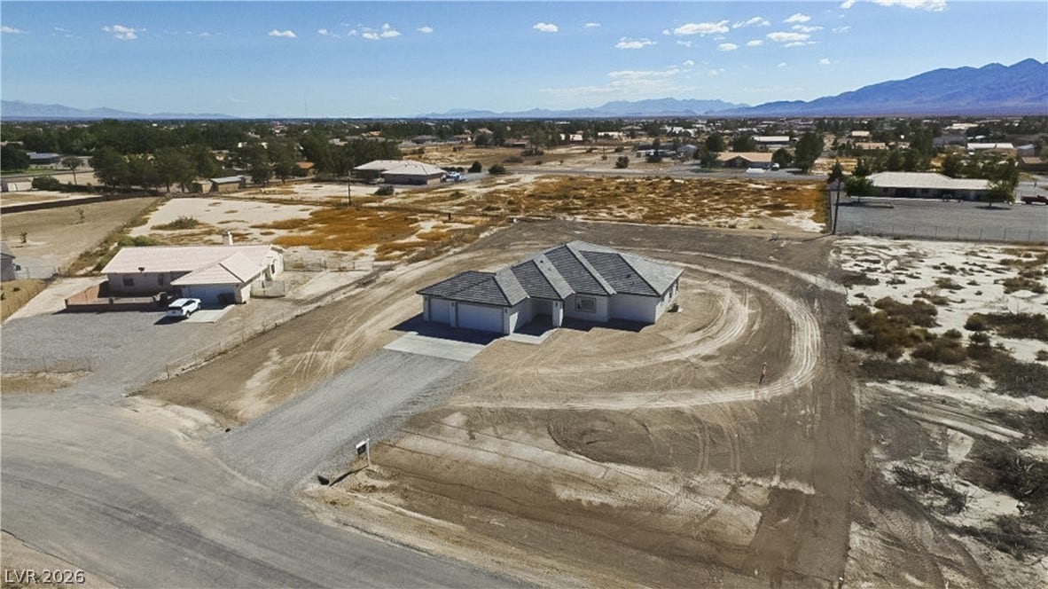 An aerial perspective showcases a newly constructed residence nestled within a vast desert landscape.