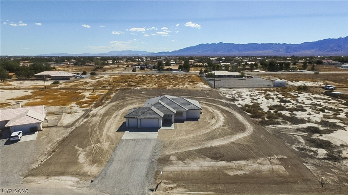 A newly constructed desert home sits on an expansive parcel framed by distant mountain ranges.