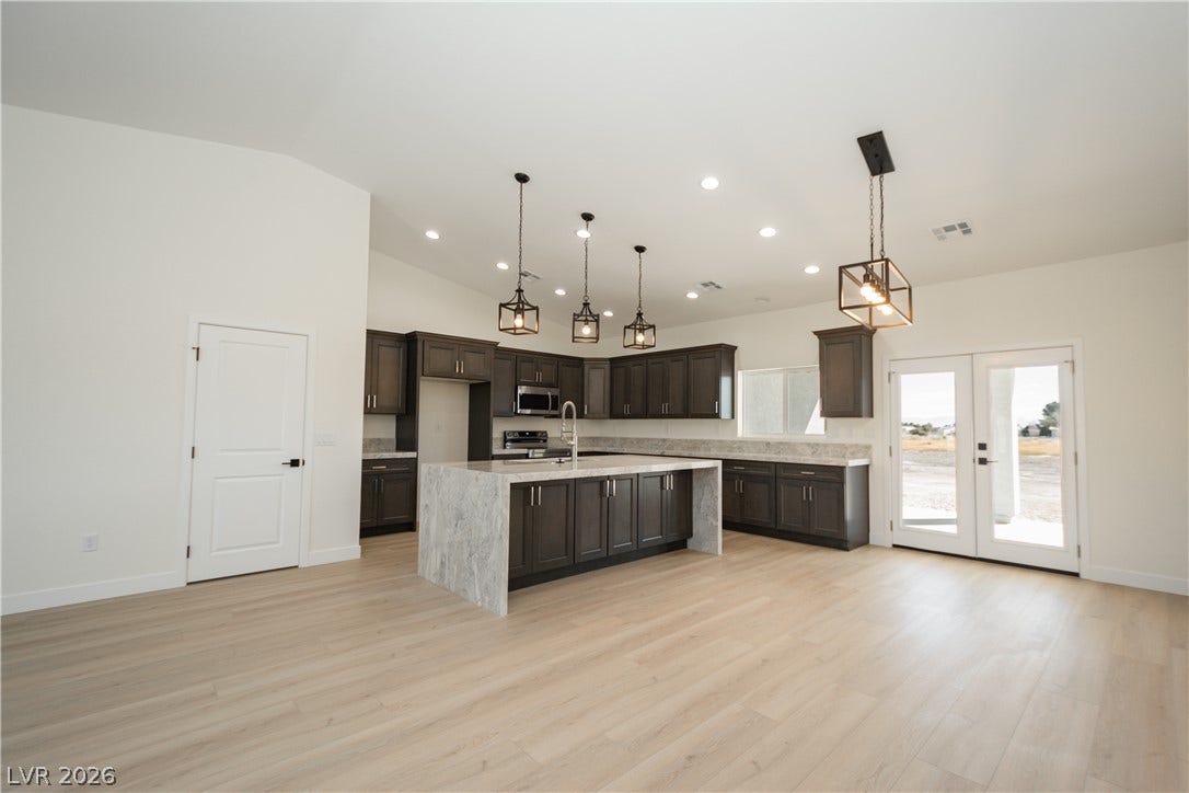 Crisp white walls and light wood flooring complement the dark cabinetry of this open kitchen.
