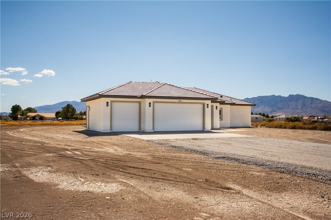 An attached three-car garage completes this modern stucco home set against a mountain backdrop.