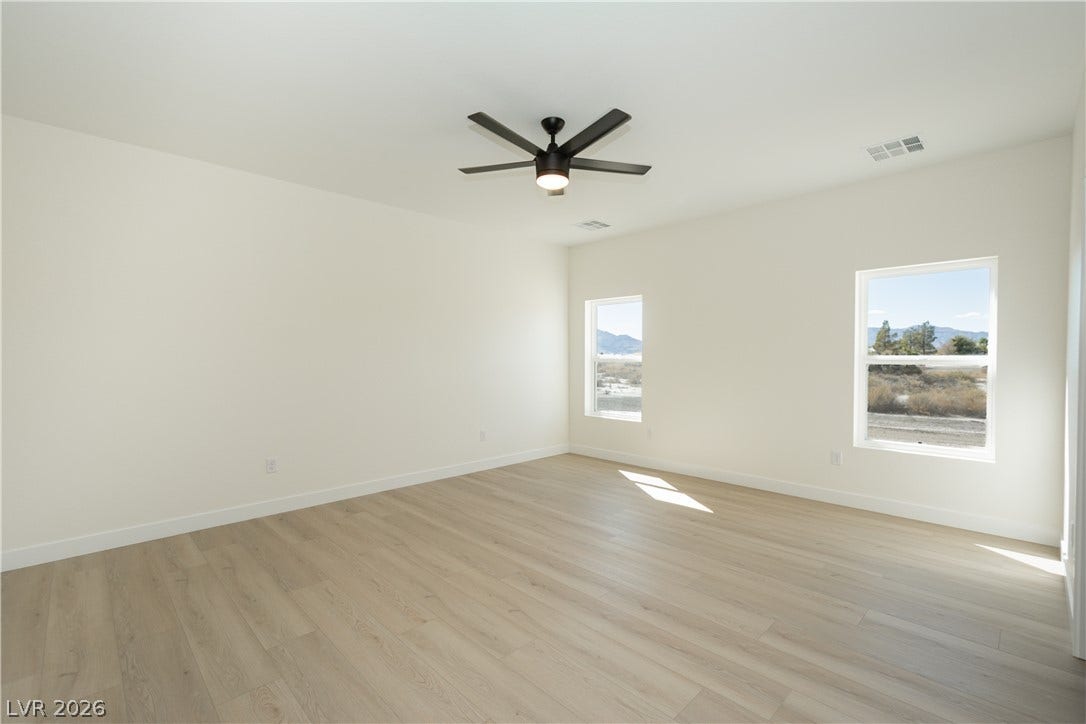 Sunlight streams across the smooth wood flooring of this minimalist, neutral-toned room.