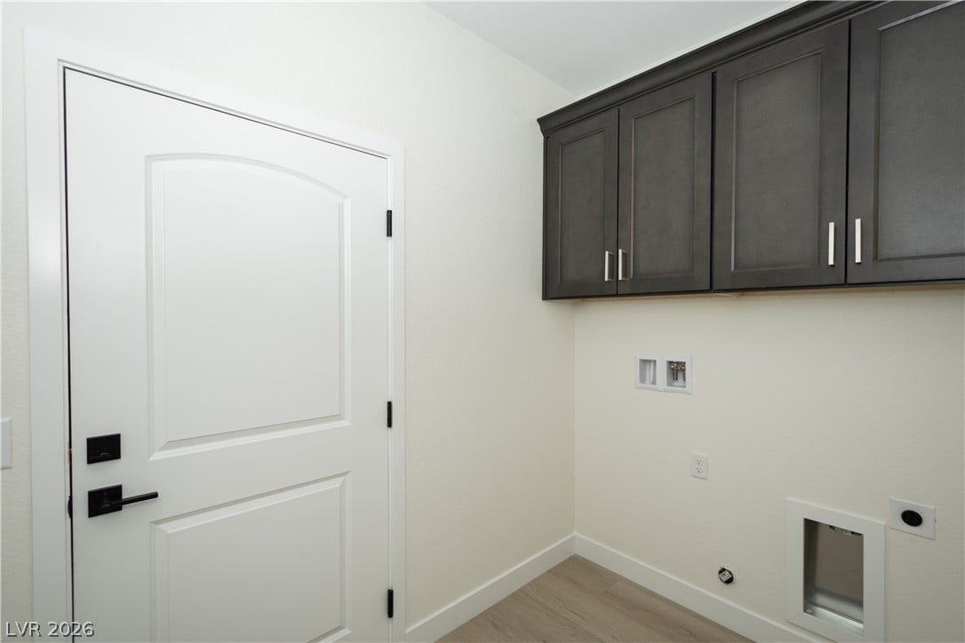Functional utility space features overhead cabinetry, hookups, and durable laminate flooring.