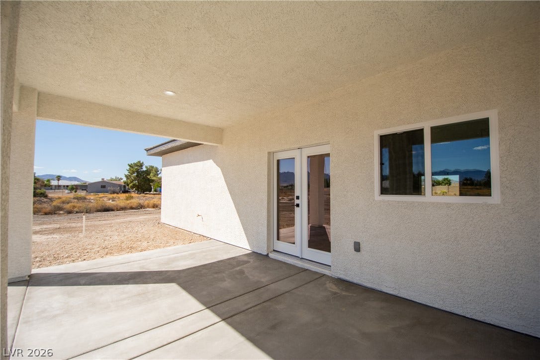 A sheltered concrete patio connects the home interior to the surrounding desert landscape.