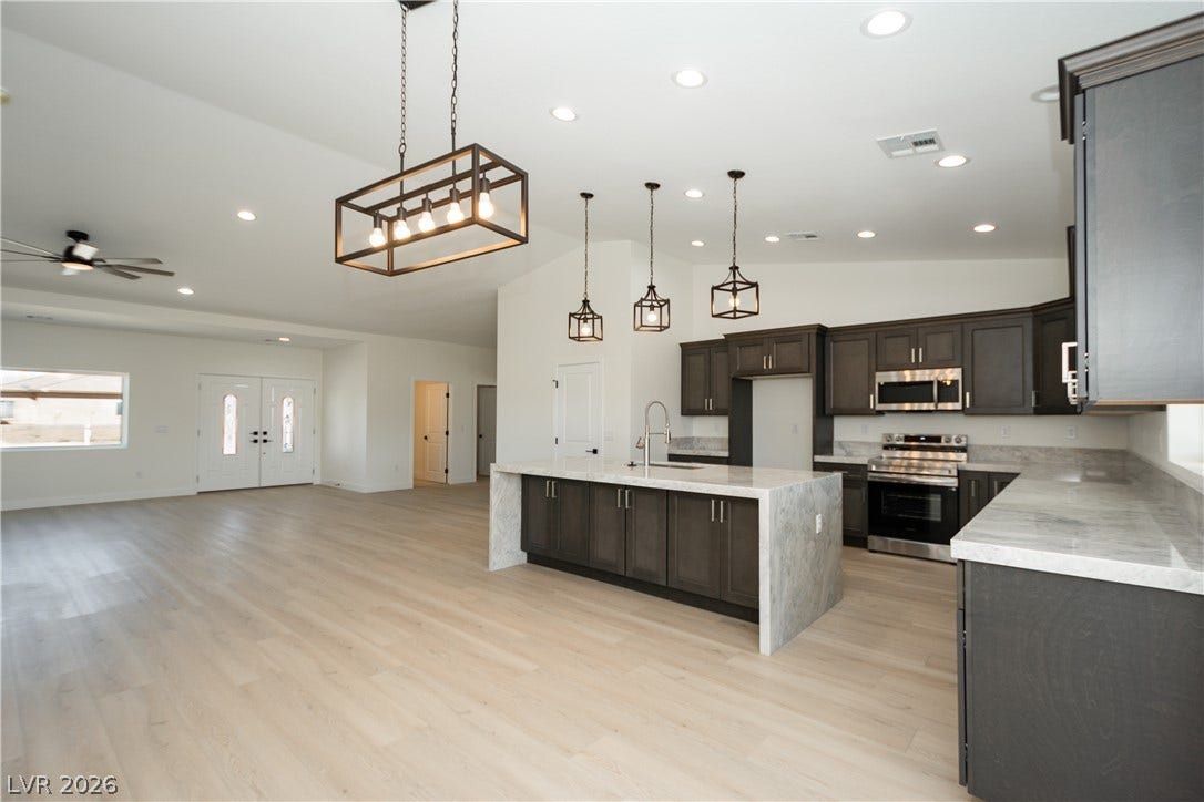An open kitchen layout flows seamlessly into the main living areas over light wood flooring.