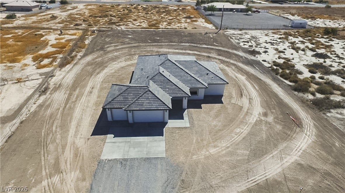 An aerial perspective showcases the tile roof and concrete driveway of this modern desert home.