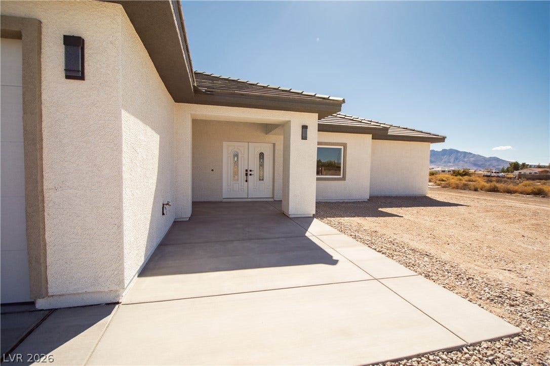 Double doors and a wide concrete walkway define this modern stucco entry.
