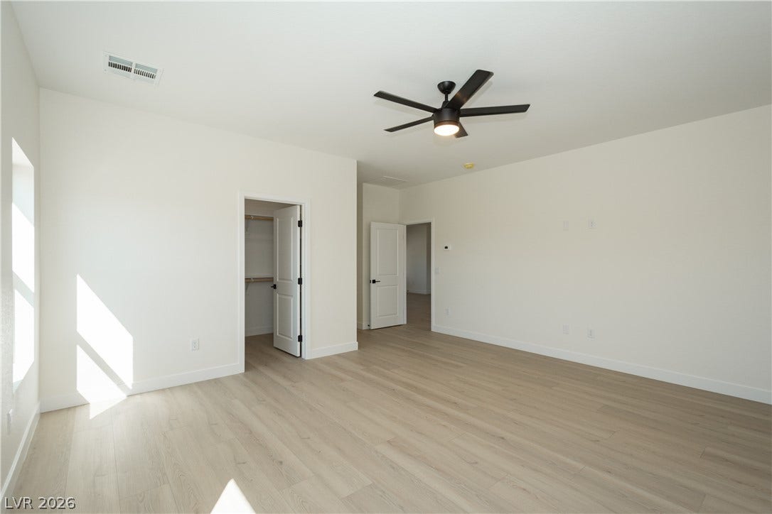 Smooth wood flooring and clean white walls create a minimalist foundation in this bedroom.
