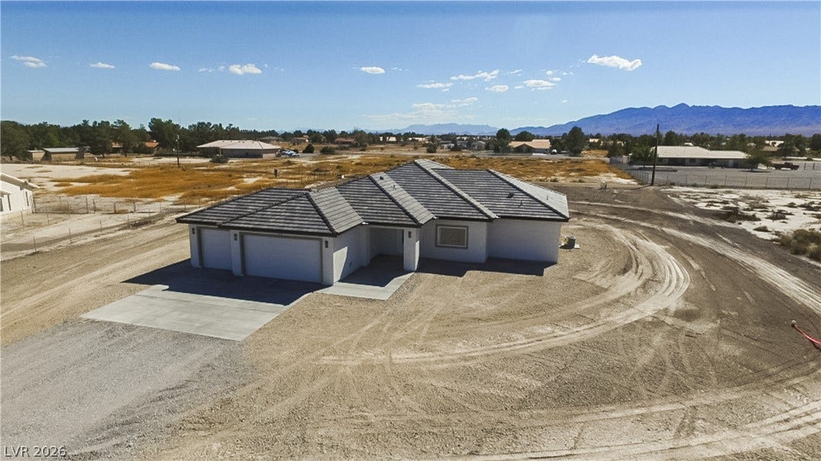 A newly constructed single-story residence stands prominently against a vast desert mountain backdrop.