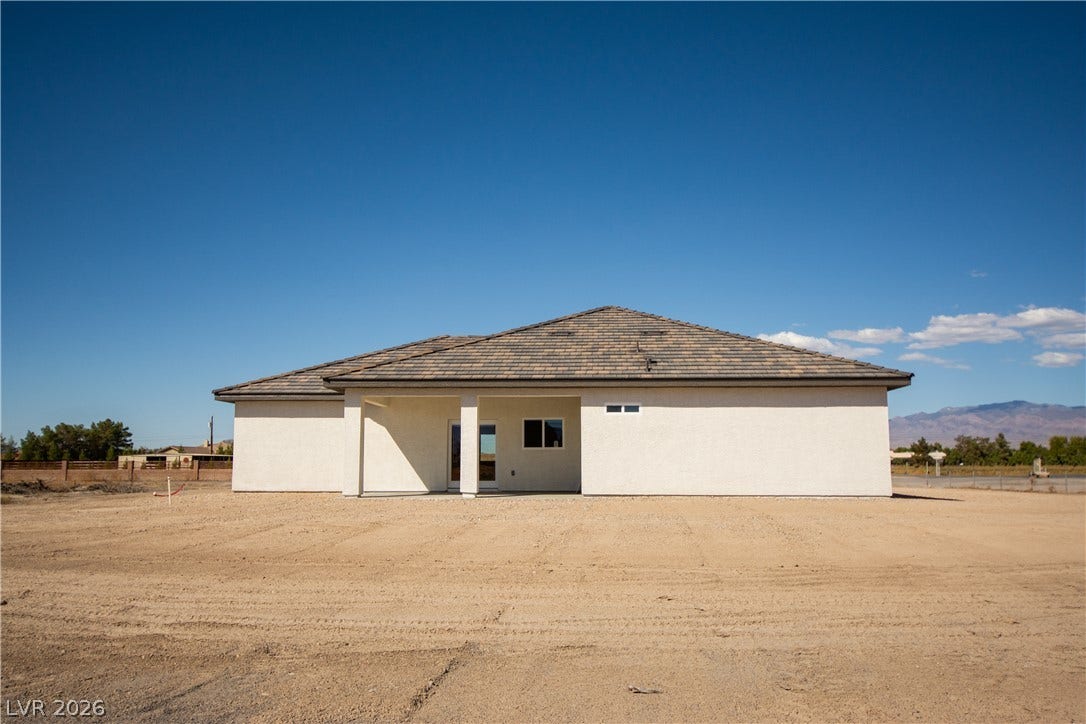 Clean stucco exterior and a covered patio define the rear of this modern home.