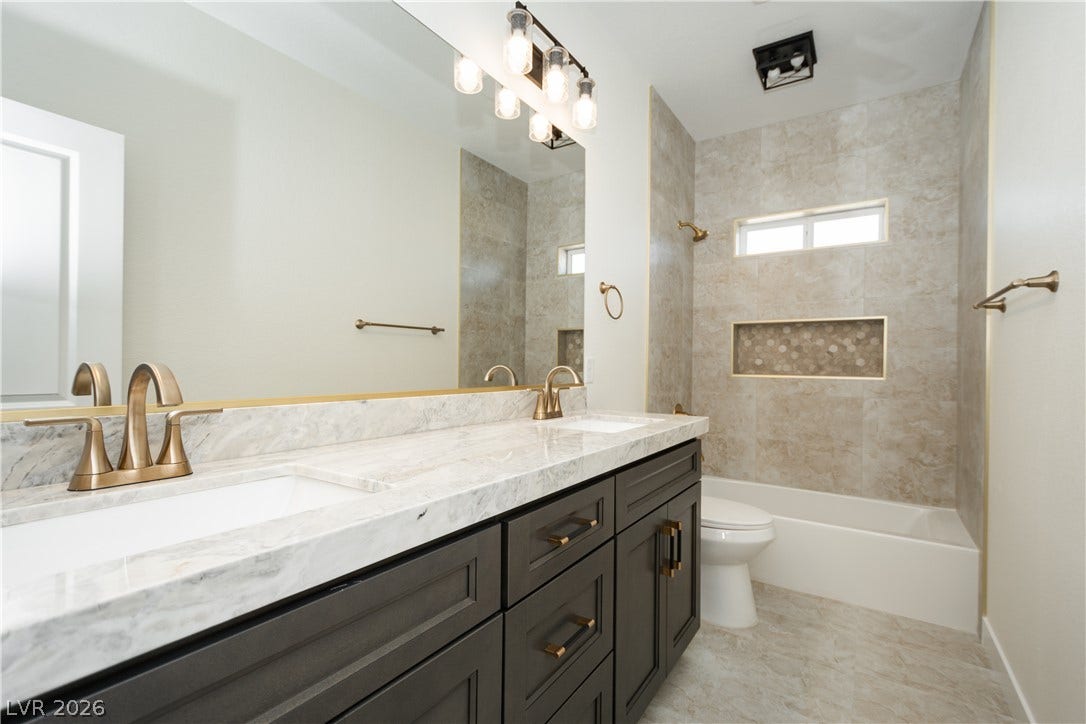 Fine stone countertops and custom tilework elevate this polished bath design.