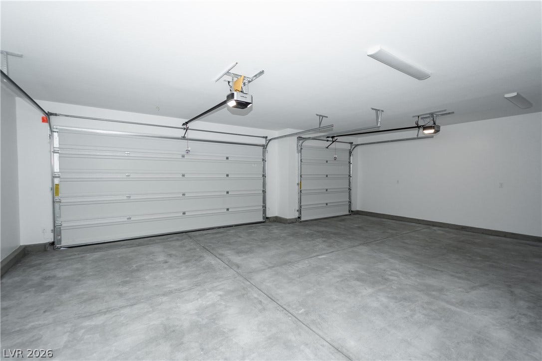 A spacious multi-car garage features durable concrete flooring and overhead automatic openers.
