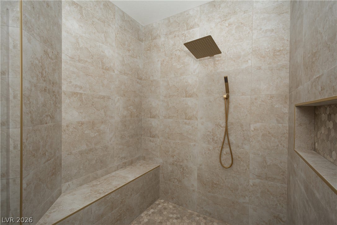 A modern walk-in shower lined with elegant floor-to-ceiling tiling and a built-in bench.