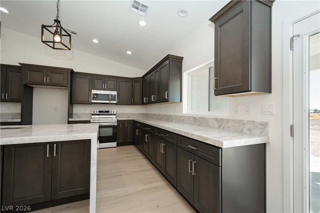 Rich dark cabinetry contrasts beautifully with light stone countertops in this modern workspace.
