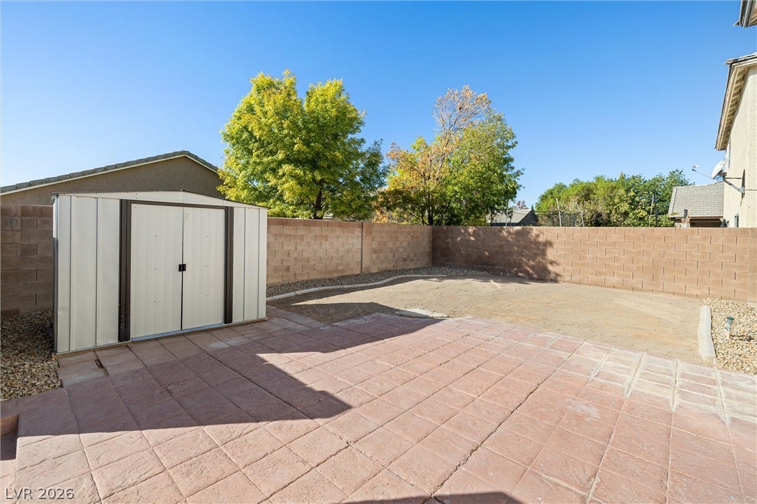 4817 Whispering Spring Avenue, Las Vegas, NV 89131 An expansive paved patio overlooks a fenced backyard complete with a functional storage shed.
