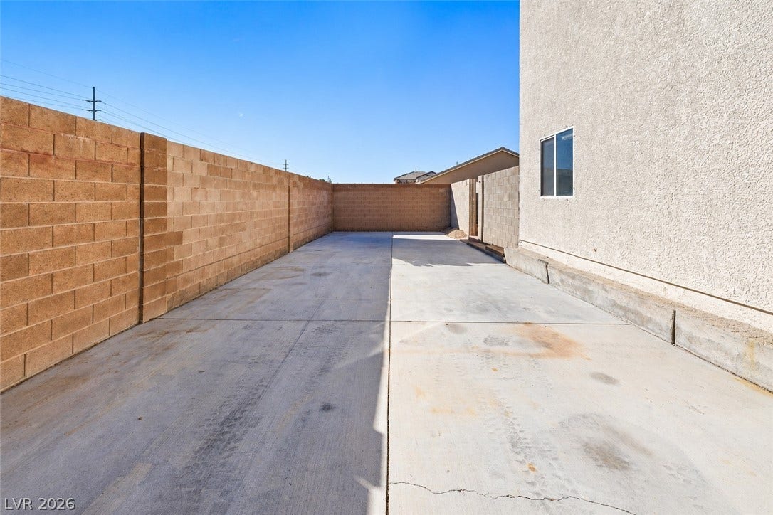 4817 Whispering Spring Avenue, Las Vegas, NV 89131 High block walls enclose a spacious concrete side yard under clear blue skies.