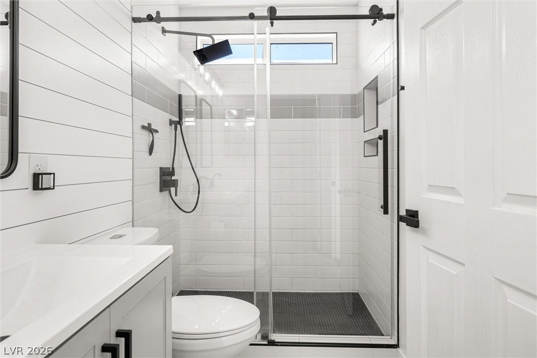 4817 Whispering Spring Avenue, Las Vegas, NV 89131 Shiplap walls and a sleek glass-enclosed shower define this modern bathroom.