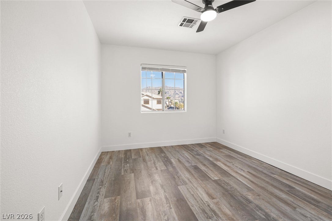 4817 Whispering Spring Avenue, Las Vegas, NV 89131 Modern plank flooring and crisp white walls frame mountain views through a central window.