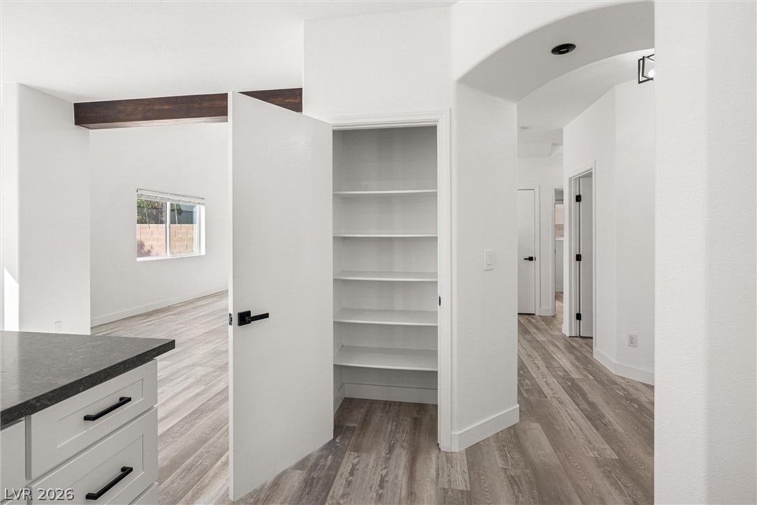 4817 Whispering Spring Avenue, Las Vegas, NV 89131 An open doorway reveals built-in pantry shelving adjacent to the hallway and main living area.