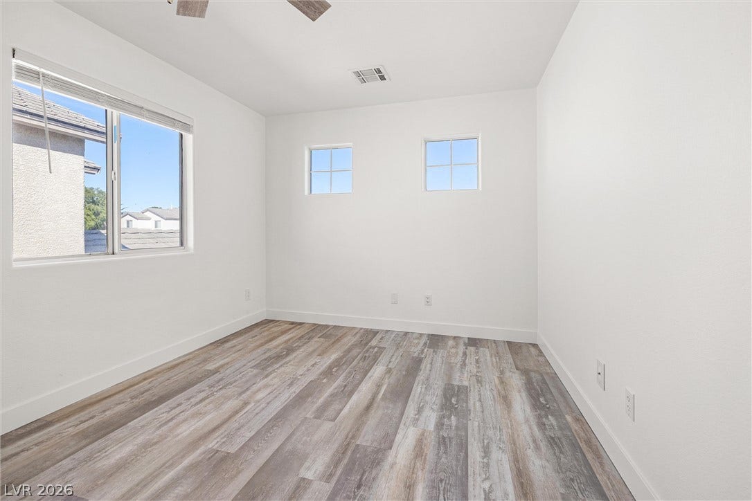 4817 Whispering Spring Avenue, Las Vegas, NV 89131 Gleaming wood-look floors complement clean white walls in this sunlit secondary bedroom.