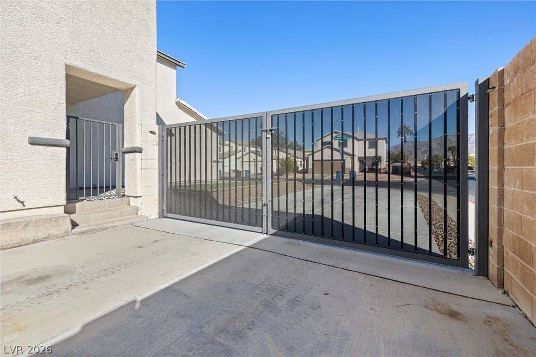 4817 Whispering Spring Avenue, Las Vegas, NV 89131 Secure gated access opens to a concrete driveway flanked by durable masonry walls.