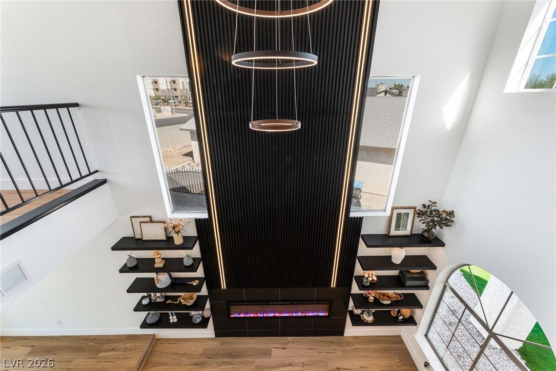 Dramatic floor-to-ceiling paneling frames a sleek modern fireplace under soaring high ceilings.