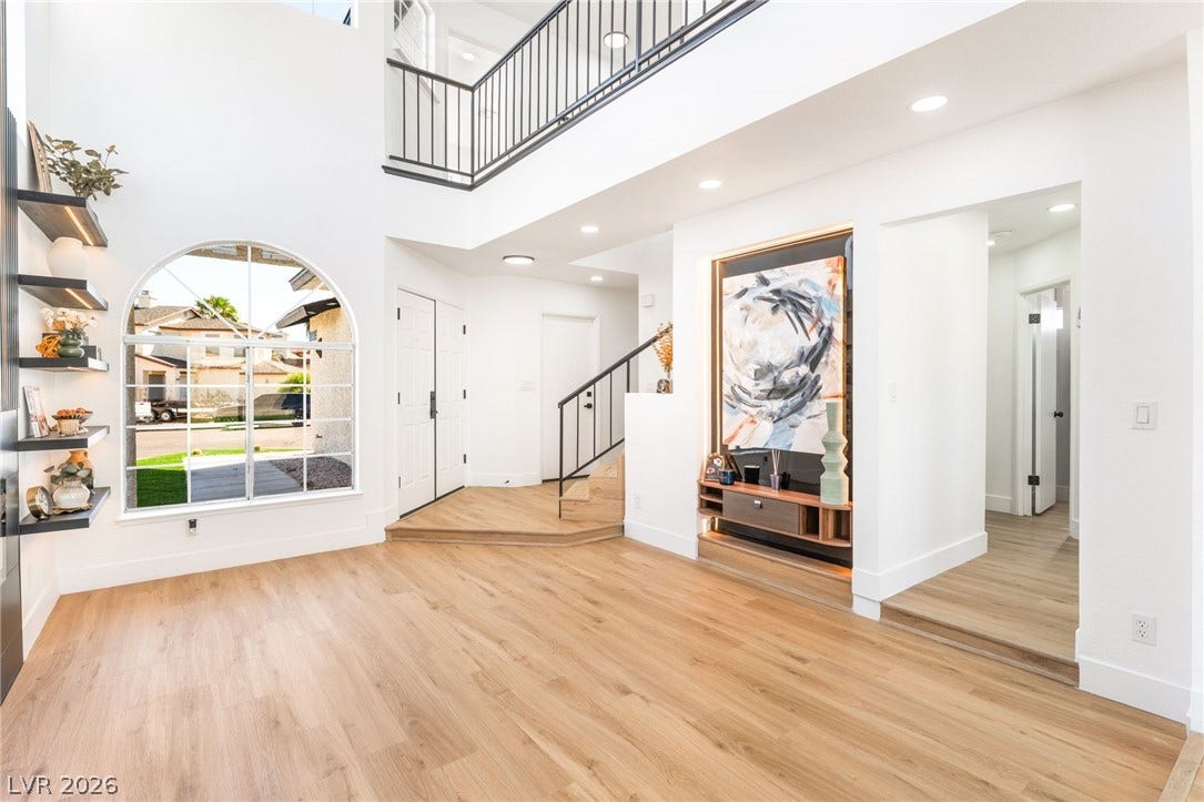 A soaring double-height ceiling and warm wood flooring define this open entrance hall.