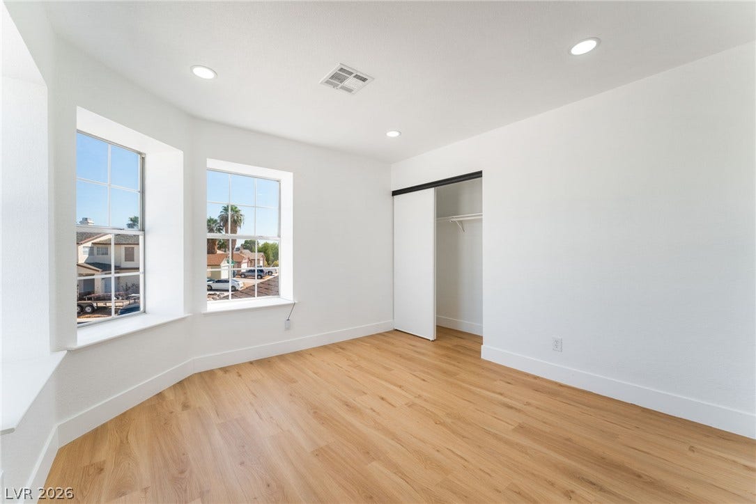 Gleaming wood floors and recessed lighting enhance this airy bedroom featuring a sliding closet door.